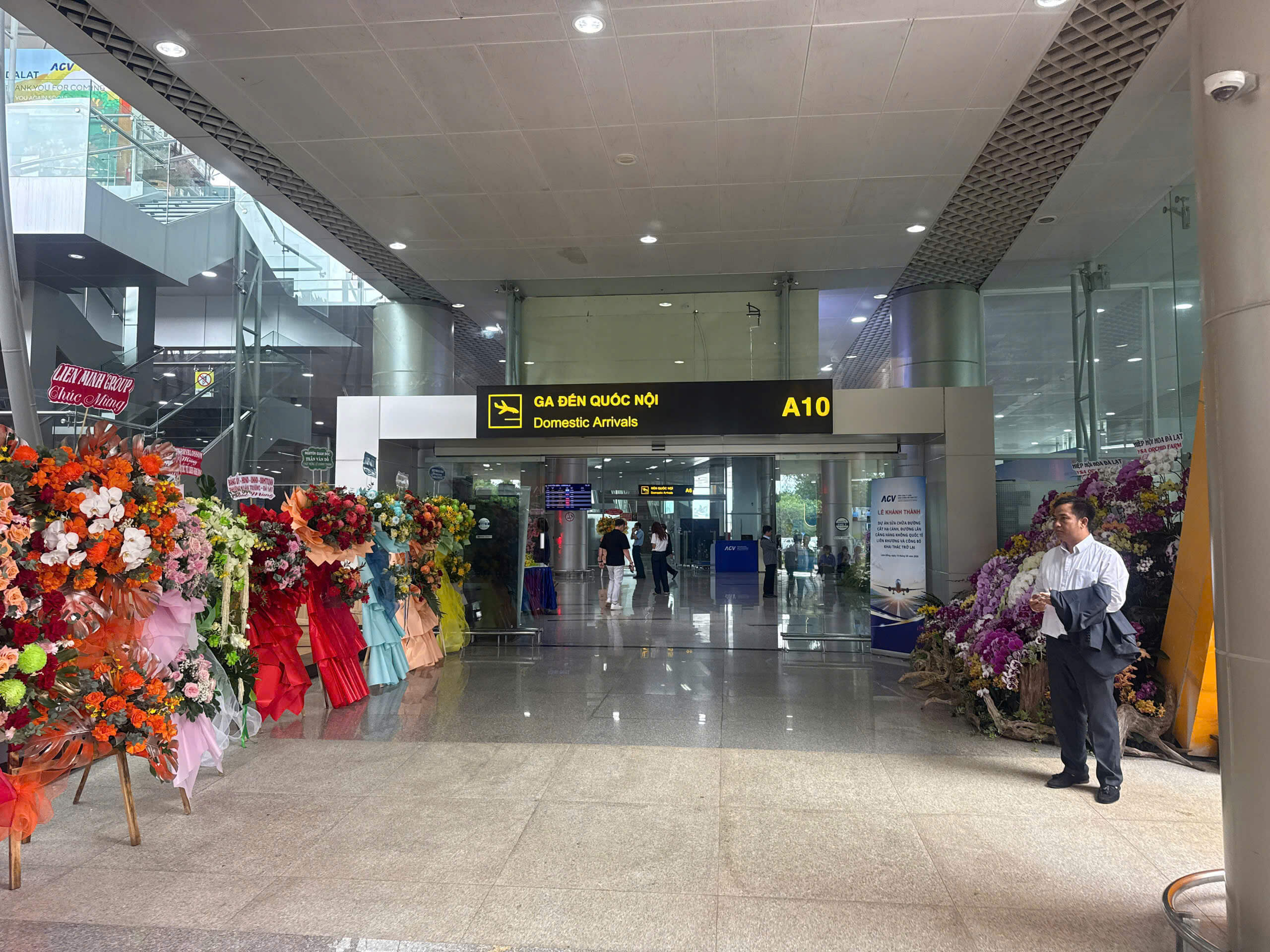 Hoa chúc mừng hai bên cửa A10 ga đến quốc nội sân bay Liên Khương Hoa chúc mừng xếp hai bên lối vào Đến quốc nội A10, khách di chuyển bên trong